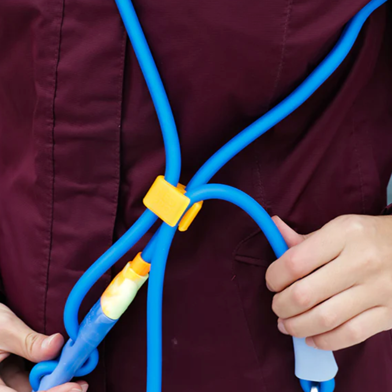 Person holding a blue handsfree leash wit a yellow connector against a blurred background
