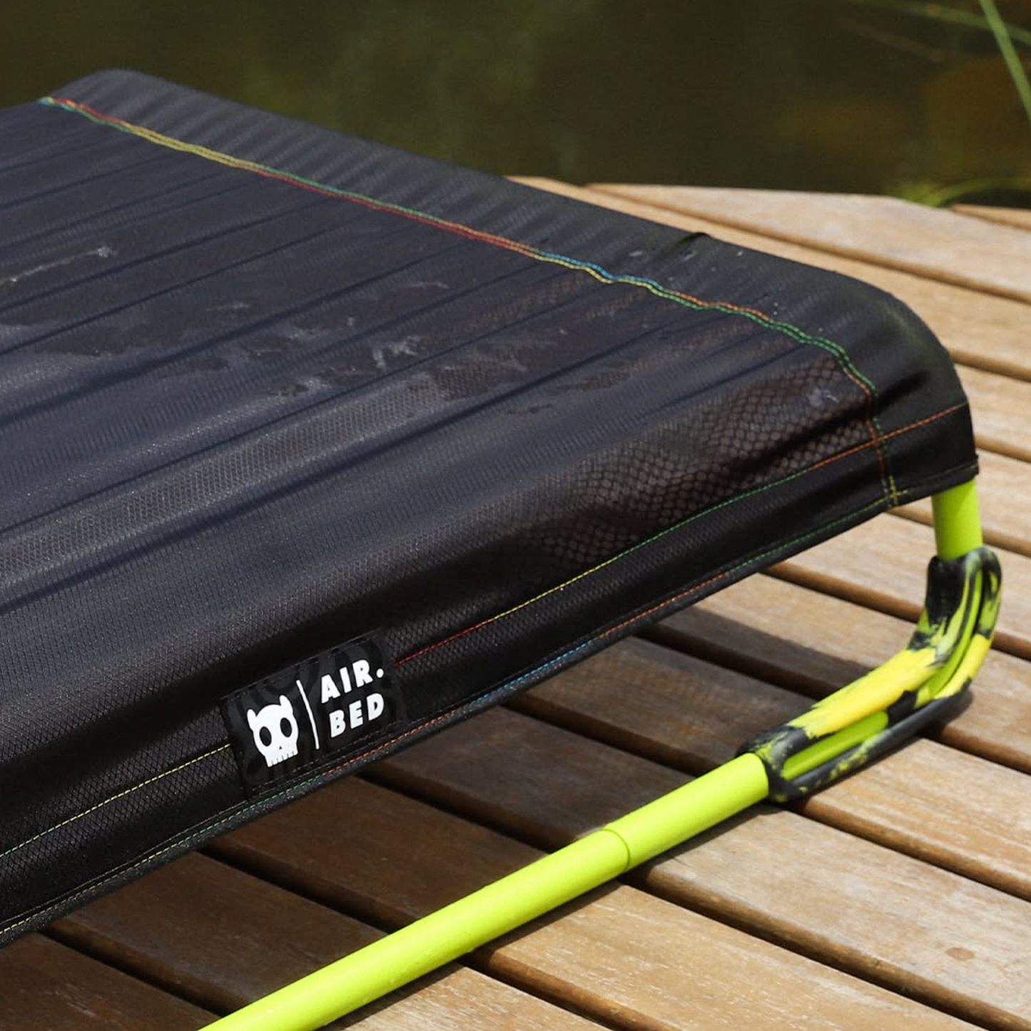 Black air bed with green handle on a wooden surface