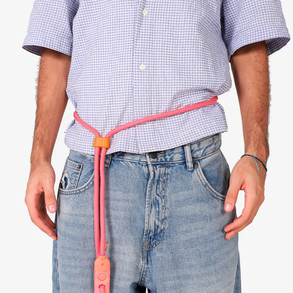 Person wearing a pink leash with an orange buckle, standing against a plain background