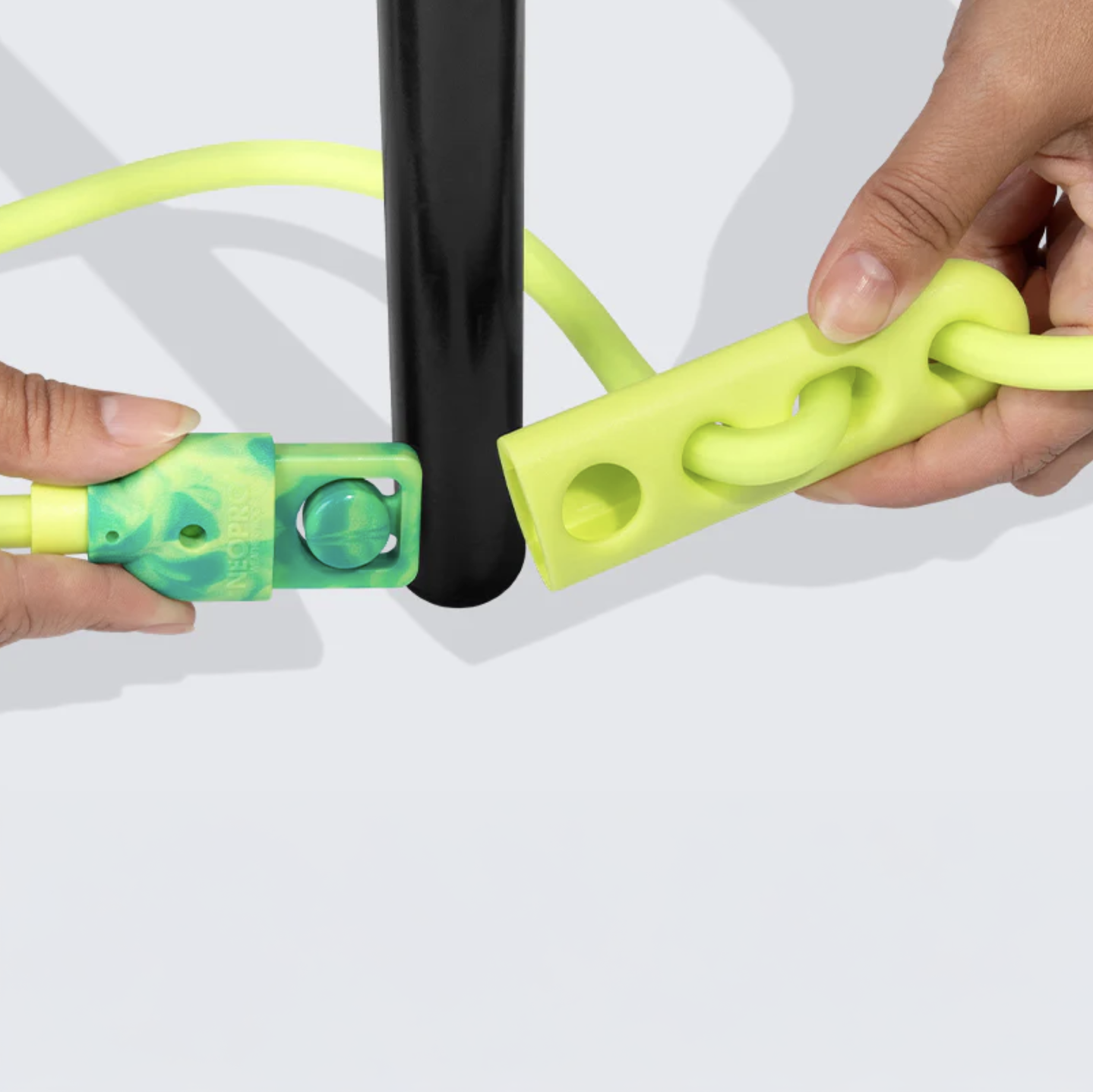 Close-up of hands using a green and yellow with hands-free leash on a black chair leg.
