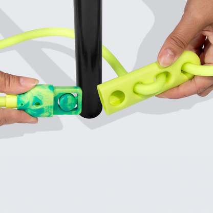 Close-up of hands using a green and yellow with hands-free leash on a black chair leg.