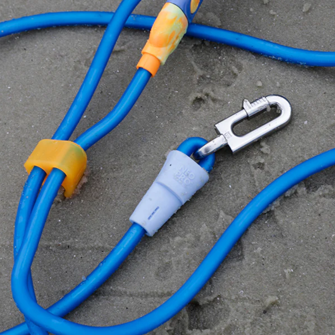 Blue dog leash with yellow connectors and a silver clasp on sandy ground
