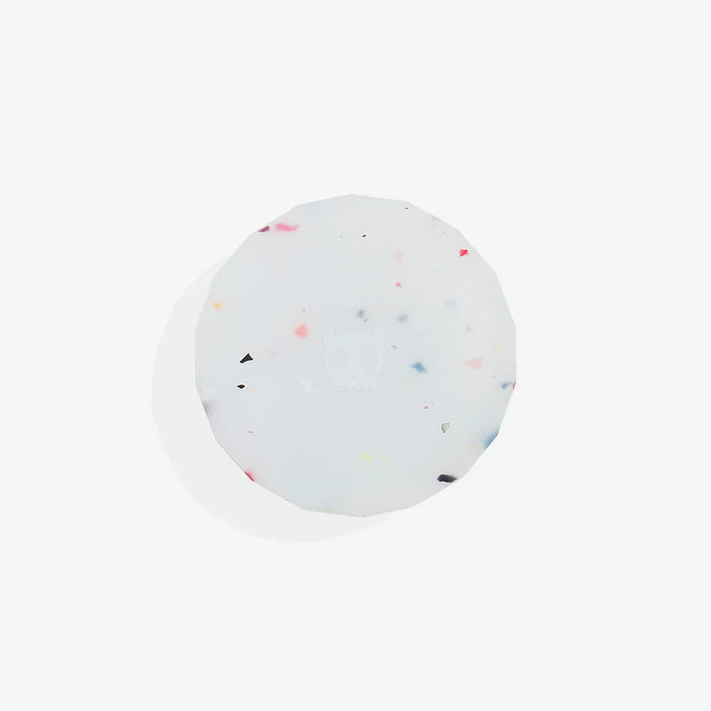 Round, white airtag holder with colourful specks on a light grey background